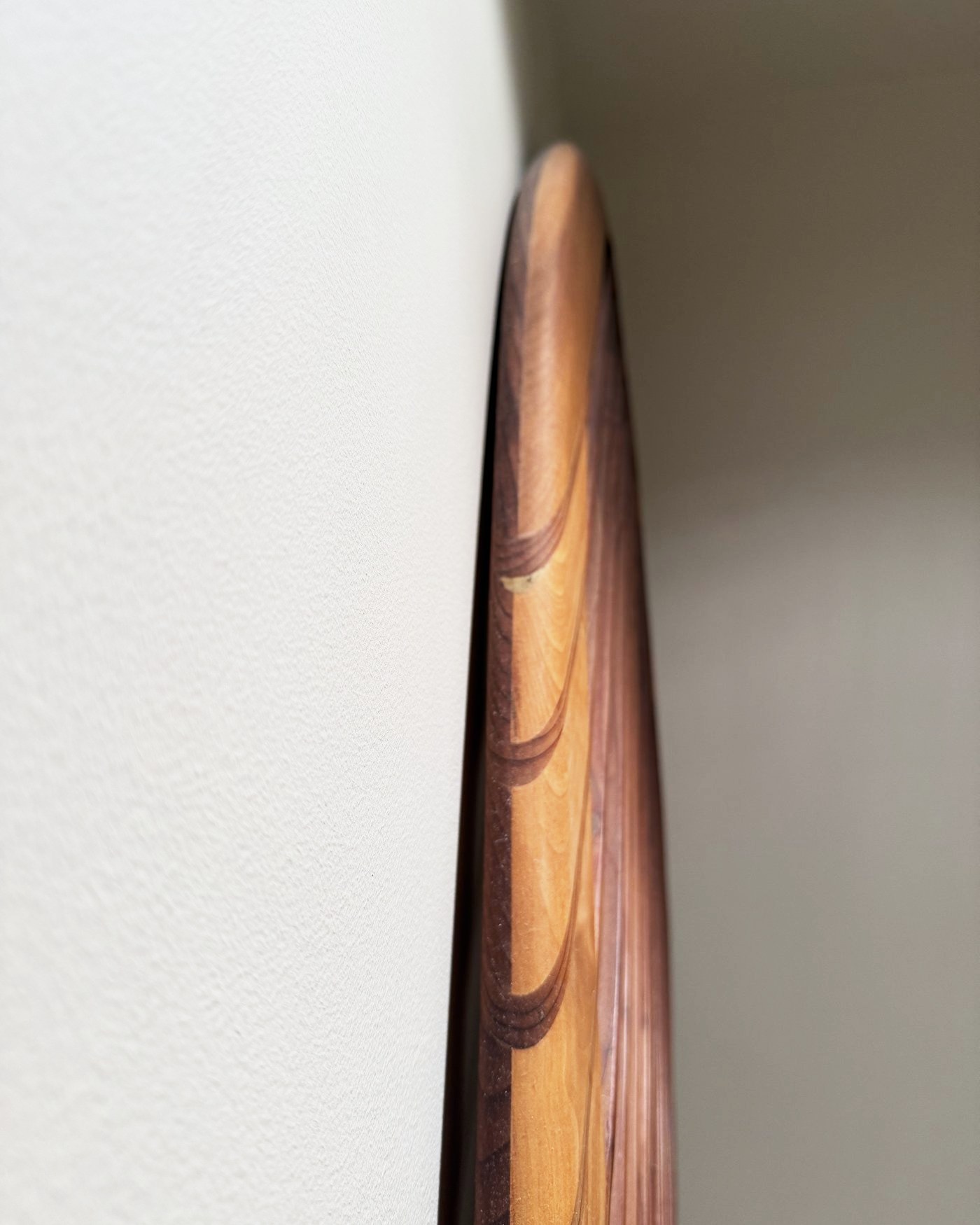 The rounded cedar rail seen edge-on against the wall.